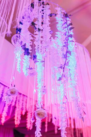 Magnificent chandeliers hang from the white ceiling pink colors. Wedding decoration of restaurantの写真素材