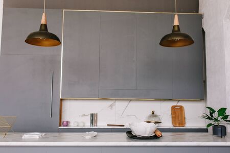 Black loft kitchen lamps in a modern style with gray cabinets, white lockers and shelves with accessories. There is a stone table topの写真素材