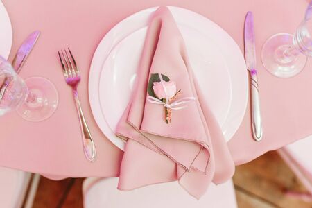 Top view of the beautifully decorated table with white plate, crystal glasses, beige napkin, cutlery and white flower on luxurious tablecloths, with space for textの写真素材