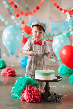 Baby boy touching his first birthday cake. Making messy cakesmash in decorated studio locationの写真素材