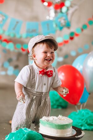 Baby boy touching his first birthday cake. Making messy cake smash in decorated studio locationの写真素材