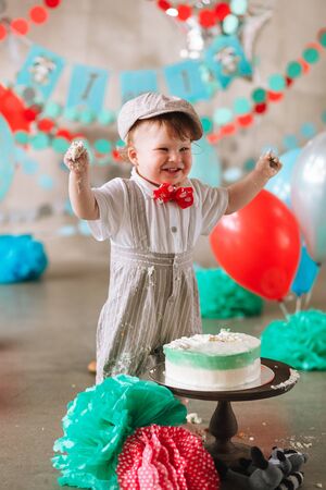 Baby boy touching his first birthday cake. Making messy cakesmash in decorated studio locationの写真素材