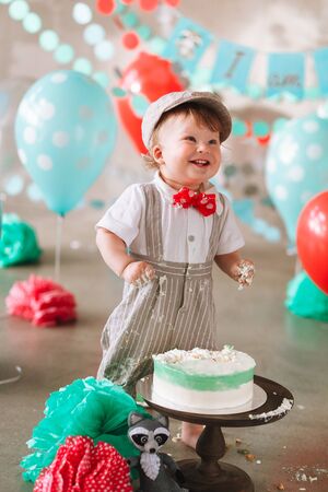 Funny baby boy laughing in his first birthday cake smash. Messy dirty handsの写真素材