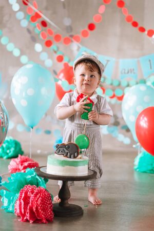 Adorable happy baby boy eating cake one at his first birthday cake smash partyの写真素材