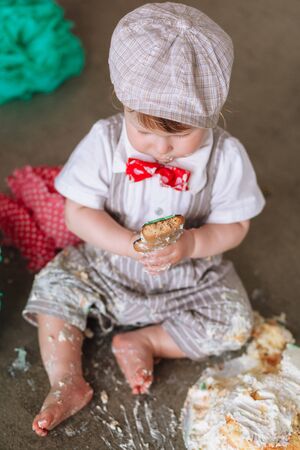 Little boy eating cake in messy decorated studio backdrop. Birthday cake smash partyの写真素材