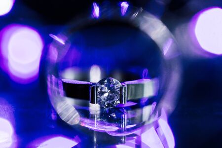 Close up diamond ring wedding ring inside circle. Creative wedding invitation card concept. Sparkling purple background with copy spaceの写真素材