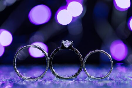 Beautiful three platinum wedding rings on sparkling purple background. Copy space for text areaの写真素材