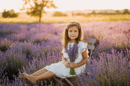 Calm Little Girl on Lavender Field with Bouquetの写真素材