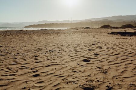 Warm Yellow Clear Sand on Summer Beach Seascape. Large Footsteps on Coastline with Blue Skyline Aqua Summer Concept. Beautiful Vacation near Shoreline Water Outdoor Sunlight Backgroundの写真素材