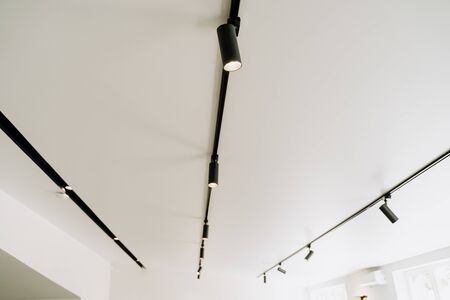 Shine Electrical Led Spot Light on White Ceiling Copy Space. Modern Stage, Museum, Exhibition Hall, Office or Apartment Illumination Equipment. Design Interior. Decorative Electric Spotlight Lampの写真素材