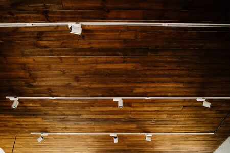 Modern Electrical Led Spot Light on Wooden Ceiling Copyspace. Retro Style Office or Apartment Room Illumination Device. Design House Interior. White Metallic Decoration Electric Spotlight Lampの写真素材