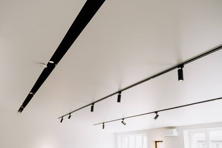 Shine Electric Led Spot Light on White Ceiling Copyspace. Stylish Store Shop, Museum, Exhibition Hall, Office or Apartment Illumination Device. Design Interior. Decorative Electric Spotlight Lampの写真素材