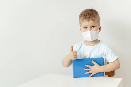 Caucasian Boy Wearing Mask Sitting with Tabletの写真素材