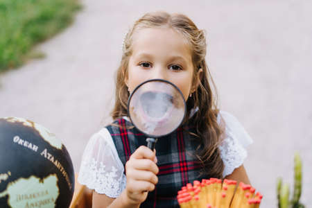 Cute Elementary Schoolgirl Smile Through Magnifierの写真素材