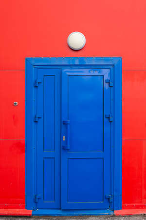 a blue door on a red wall with a lamp on the wallの写真素材