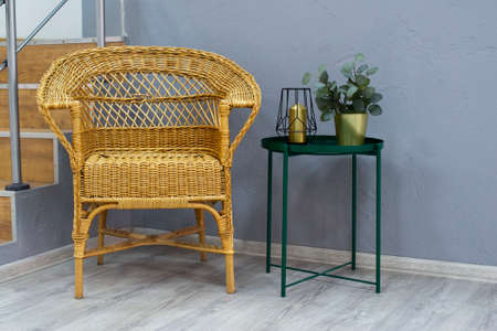 a wicker chair stands next to a table in the roomの写真素材