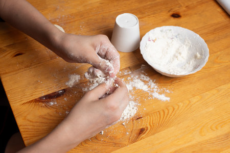 the hands work with flour and dough on a wooden table