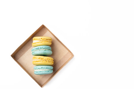 the yellow and blue macaroons lie in a cardboard box on a white backgroundの写真素材