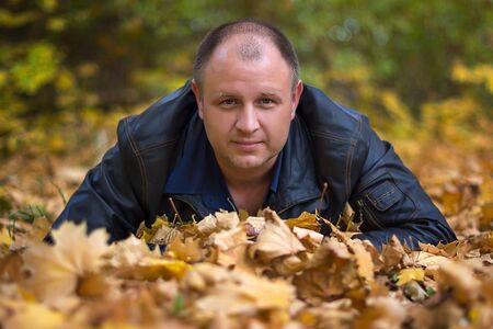 happy the man lying on the ground in autumn leavesの写真素材