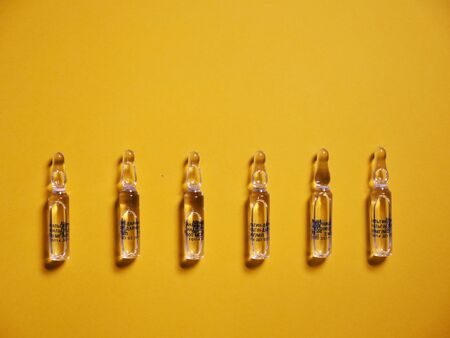 Coronavirus Covid19. Ampoule on a yellow background