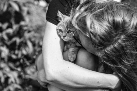 Young woman hugging a kitten of the Scottish Straight breed. Black and white photo close up outside. High quality photoの写真素材