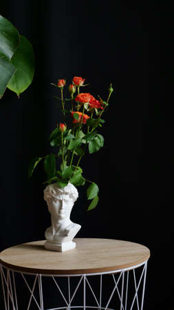 Orange rose bush flower on isolated black background in original vase sculpture of David. Gift for a woman, mother, grandmother, wife on March 8, Women's Day, Mother's Day, birthday, Valentine's Dayの写真素材