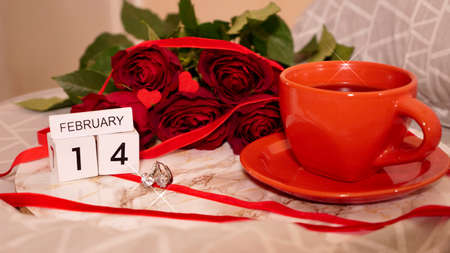 Background Festive Flatlay, composition for Valentines Day on February 14. Coffee in a red cup, red rose flowers and diamond heart earrings at home in bedの写真素材