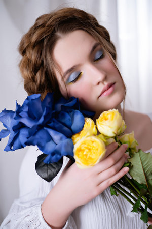 Portrait Caucasian Ukrainian girl in a white dress and flowers on white background . Symbol of the Ukrainian yellow blue colour. The calm lady is asleep. Concept - Stop War in Ukraine.の写真素材