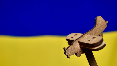 Decorative wooden toy plane on the yellow blue background of the Ukrainian flag. Russia attacked Ukraine in 2022の写真素材