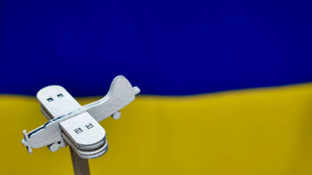 Decorative wooden toy plane on the yellow blue background of the Ukrainian flag. Russia attacked...