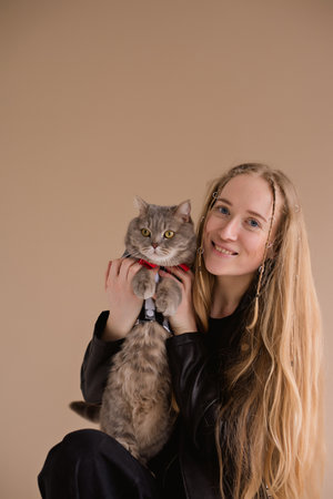 A woman natural blonde smiling in a black clothes stand, sitting on photo studio. girl with pet scottish straight cat. long hairの写真素材