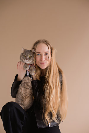 A woman natural blonde long hair smiling in a black clothes stand, sitting on photo studio. girl...