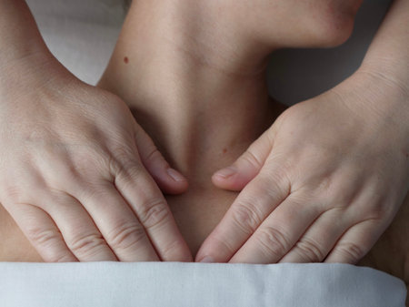 The masseur massages the client in the thoracic area of the collarbone. Close-up, no faceの写真素材
