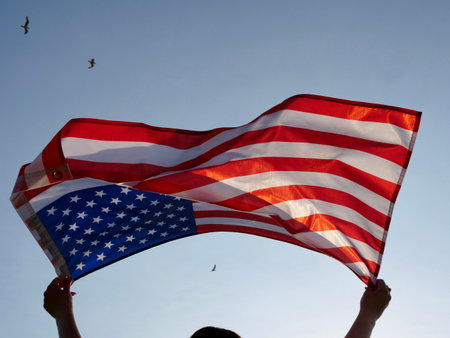 Independence Day American flag against the background of the blue sky blowing in the wind. close up