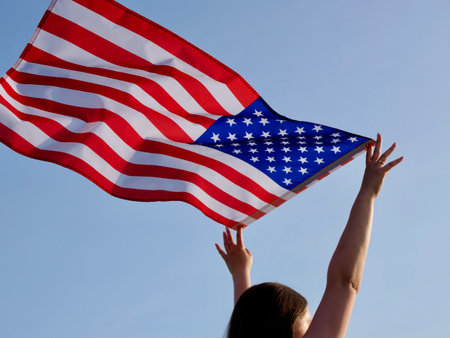 USA flag waves against a clear sky, symbolizing American freedom and patriotism. Its perfect for celebrating Constitution Day and national prideの写真素材