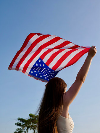 Independence Day American flag against the background of the blue sky blowing in the wind.