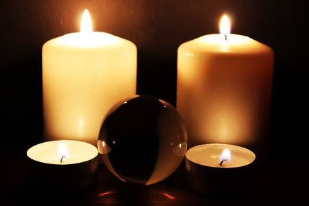 Glass ball and burning candles in the darkの写真素材