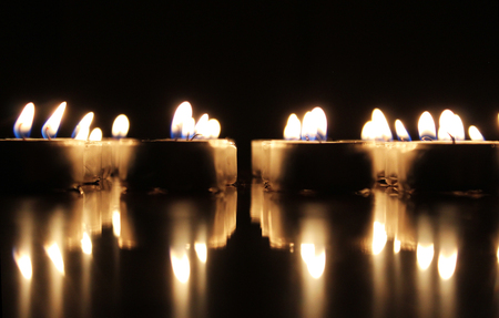 Burning candles on reflective surfaceの写真素材