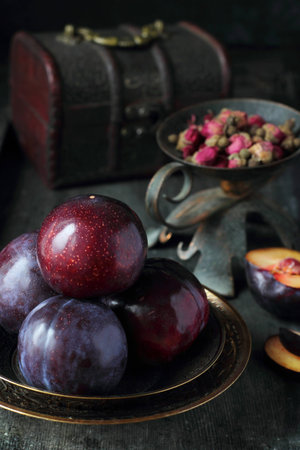plums on two metal saucer on dark wooden backgroundの写真素材