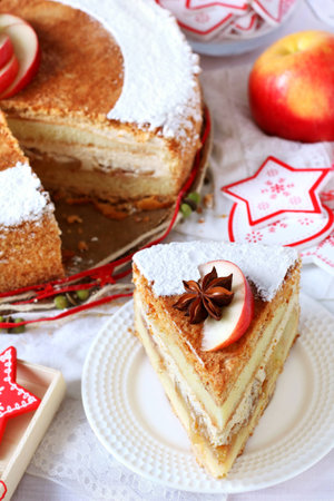 piece of Christmas homemade apple cake with cinnamon dusted with powdered sugar on a white...