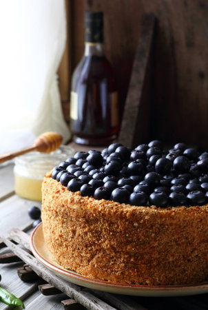 Homemade honey cake decorated with blueberry on a wooden backgroundの写真素材