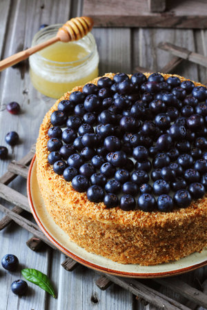 Homemade honey cake decorated with blueberry on a wooden background, top viewの写真素材