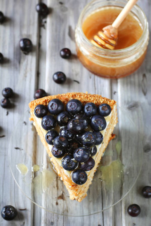 Piece of honey cake decorated with blueberry and honey on glass dish, top viewの写真素材