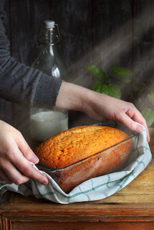 Cake with orange marmalade, honey and cinnamon in a glass form in a female hand, picture with artificial sunlightの写真素材