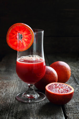 blood oranges and juice of blood oranges on a wooden background, shot with natural lightの写真素材