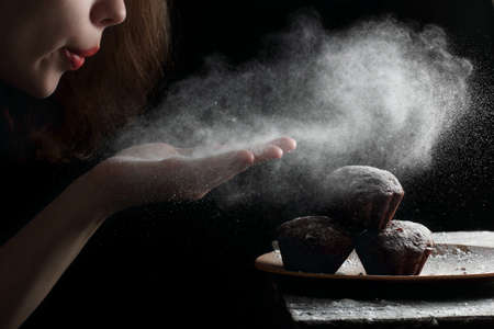 blowing powdered sugar with hands on the muffins, photographed with the light from one flashの写真素材