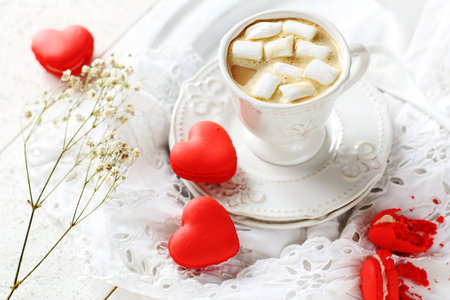 red macaroon in the shape of heart and coffee with marshmallowの写真素材