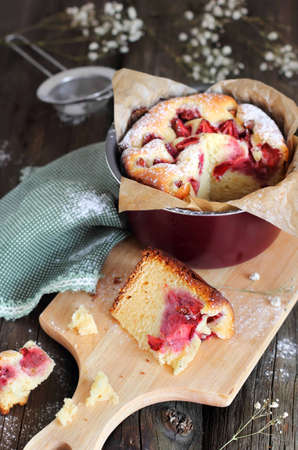 piece of homemade strawberry cake on a cutting board on a wooden backgroundの写真素材