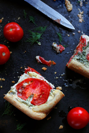 piece of cake with tomato and cheese on a black backgroundの写真素材