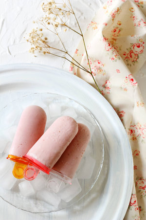 three homemade strawberry ice pops on a white backgroundの写真素材